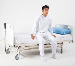 uomo seduto su un letto indossa un Pigiama di contenimento