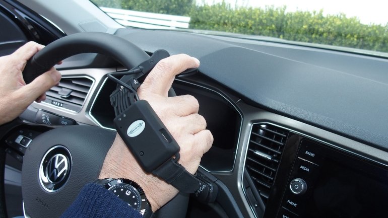 dettaglio della mano sul volante di un uomo che indossa l'acceleratore wireless 