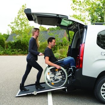 ragazza spinge in auto un ragazzoi in carrozzina