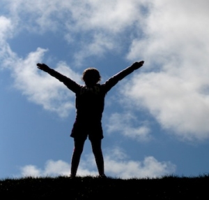 persona di spalle con braccia aperte su sfondo di nuvole