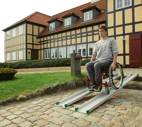 rampa per carrozzina usata da ragazzo in carrozzina per superare gradini