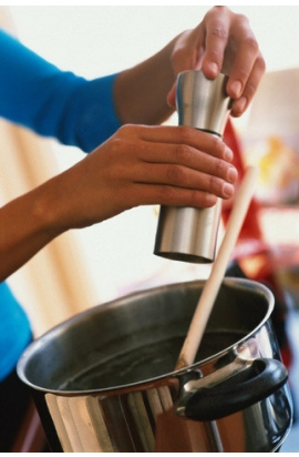 primo piano di mani che versano il pepe dentro una pentola