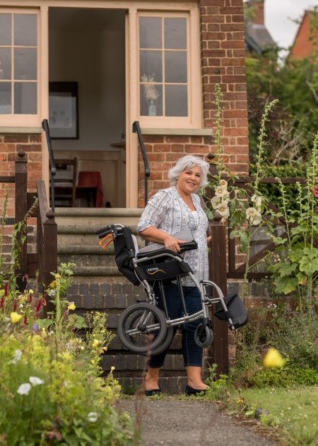 donna sta scendendo le scale di casa tenendo in mano senza difficoltà una carrozzina richiusa