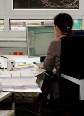 in un ufficio, una donna di spalle mentre lavora ad un pc sulla scrivania