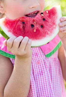 bambina che mangia una fetta d'anguria