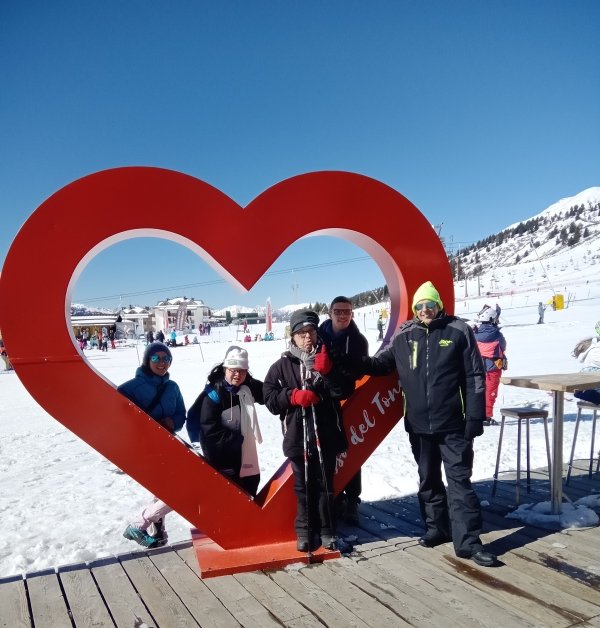 foto di gruppo di persone disabili e non in una località montana, con montagne innevate sullo sfondo