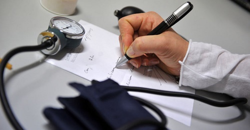 mano che scrive un certificato medico e stetoscopio