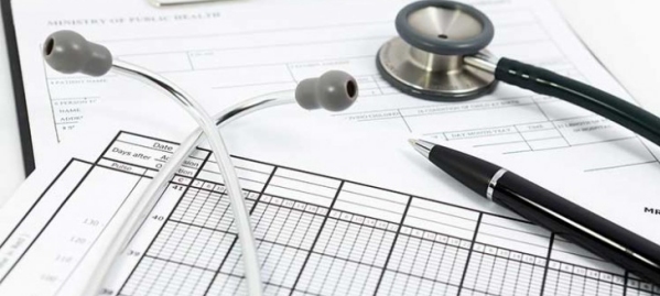 uno stetoscopio sopra dei moduli da compilare con a fianco una penna