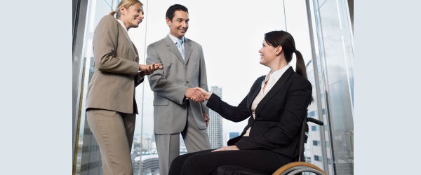 donna disabile in carrozzina stringe la mano a due consulenti