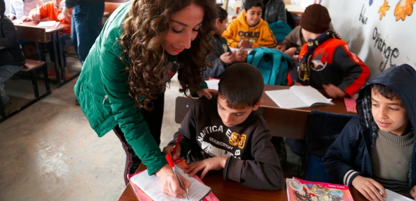 Immagine di insegnante che aiuta due bambini in un aula scolastica