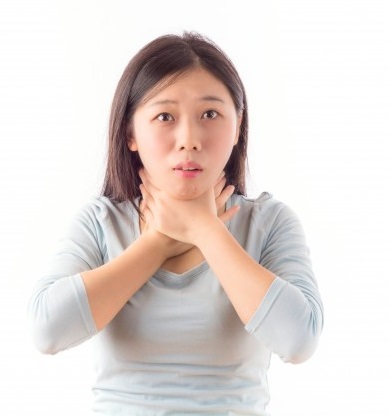 ragazza che si tiene le mani alla gola per il bruciore