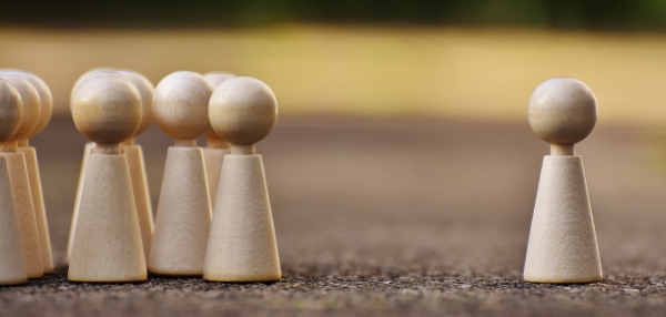 gruppo di pedine di legno sulla sinistra contrapposte ad un'unica pedina sulla sinistra