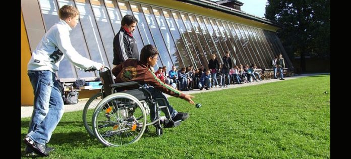 bambini su un campo che giocano tra cui un ragazzo in carrozzina