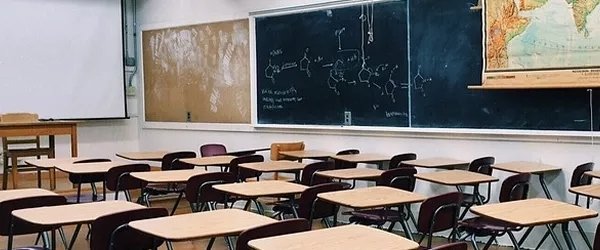 classe scolastica con banchi vuoti, lavagna e cartina geografica