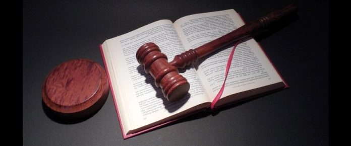 un libro aperto con sopraa un martelletto di legno