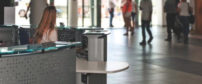 una ragazza di spalle di fronte ad un doppio bancone di un ufficio