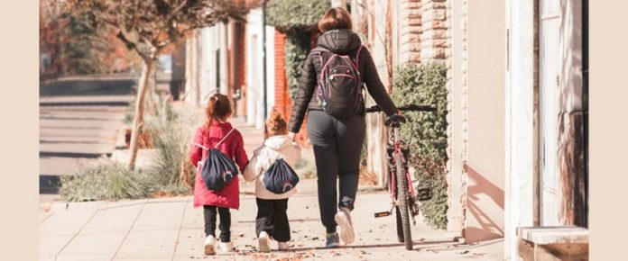 una mamma di spalle che accompagna le sue figlie