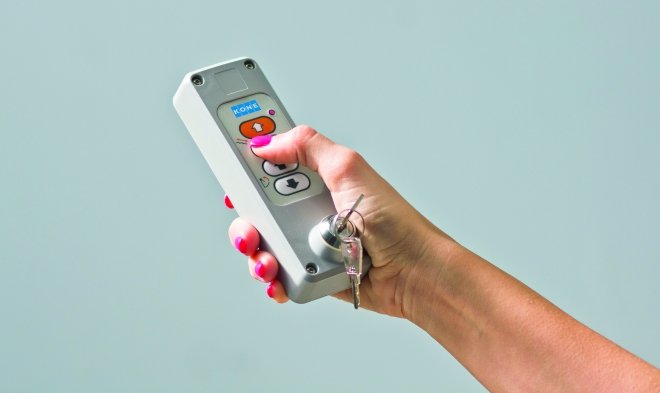 mano che preme un pulsante del telecomando per gestre la pedana disabili