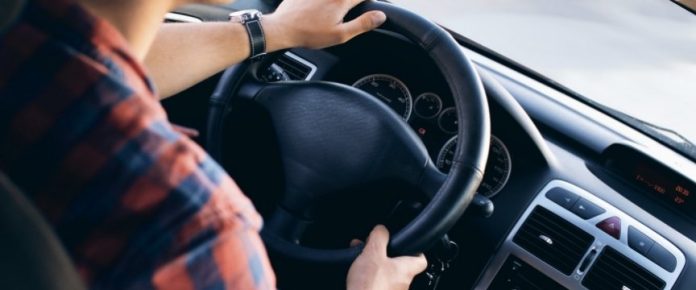 dettagli delle mani di un uomo sul volante di una macchina