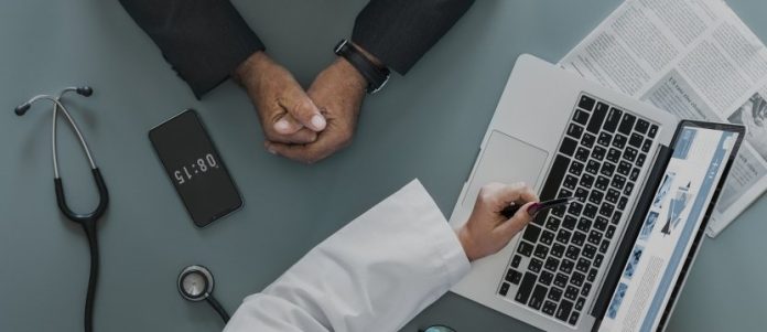 scrivania con le mani di un paziente e quelle di un dottore