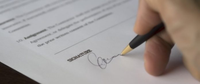 una mano che firma un modulo