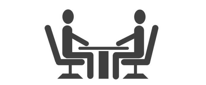 scrivania con due persone sedute una davanti all'altra