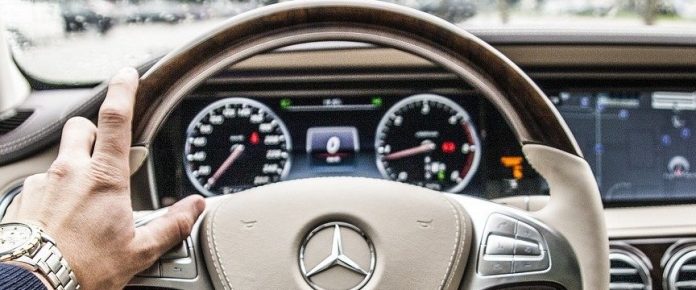 dettagli delle mani di una persona sul volante di un'auto