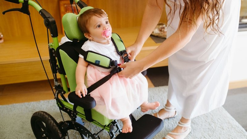 adulto aggancia le pettorine di buddybrace cted su cui è seduta una bambina