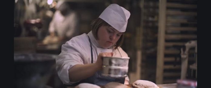 ragzza con sindrome di down mentre lavora in un laboratorio di un panificio