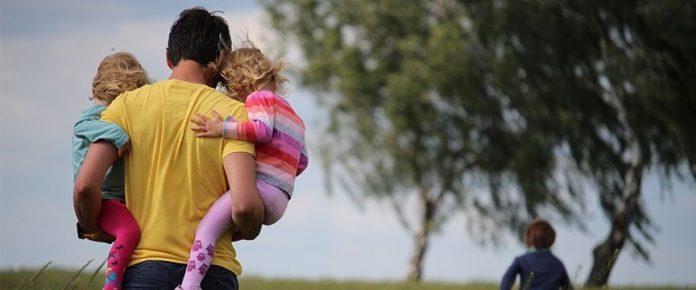 papà di spalle con due bambini in braccio