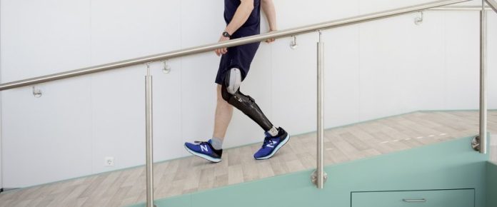 dettaglo della ortesi indossata ad una gamba da parte di un uomo che scende una rampa