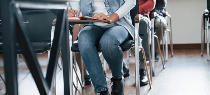 dettagli dei piedi dialcune persone sedute una dietro l'altra su banchi