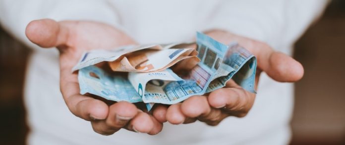 alcune banconote di euro nei palmi di due mani aperte