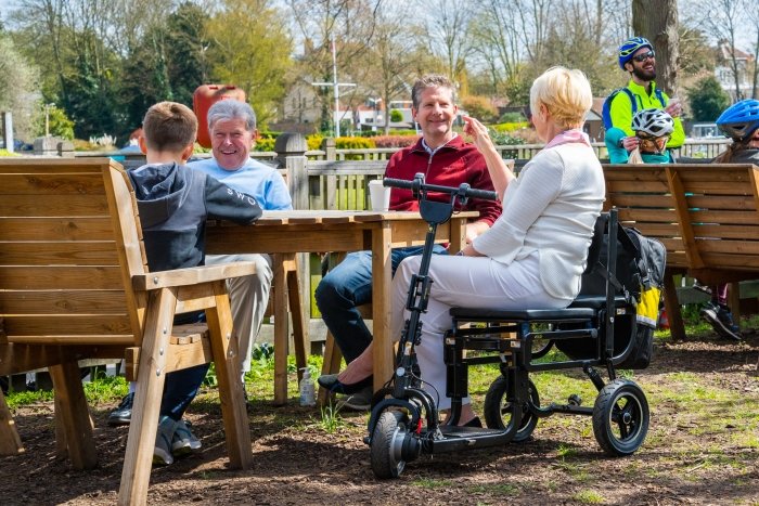 signora sullo scooter seduta al tavolo con alcune persone