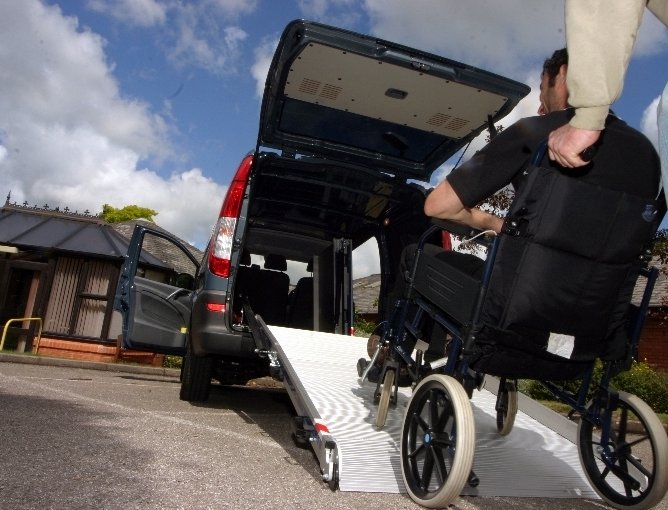 un uomo spinge la carrozzina di un passeggero in auto 