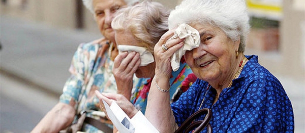 tre signore anziane sedute su una panchina si asciugano il sudore della fronte con un fazzoletto