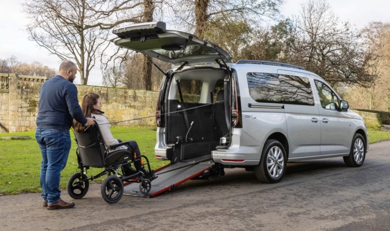 uomo spinge una ragazza in carrozzina sulla rampa posteriore di accesso al Caddy maxi