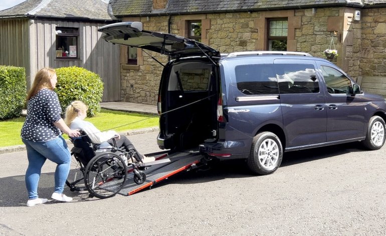 donna spinge una ragazza in carrozzina sulla rampa per salire a bordo del ourneo connect long allestito