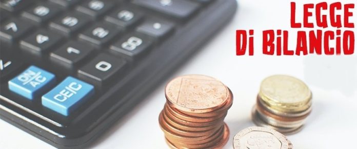 dettaglio di una calcolatrice con alcune monete e la scritta legge di bilancio