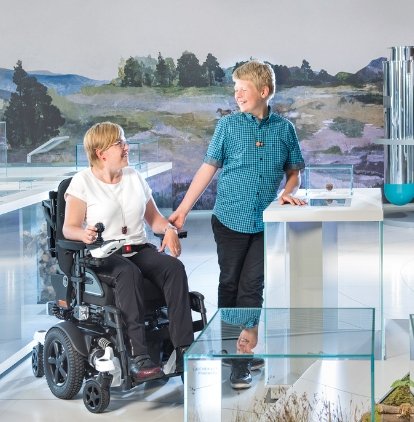 donna seduta sulla carrozzina juvo in un museo, insieme ad un bambino