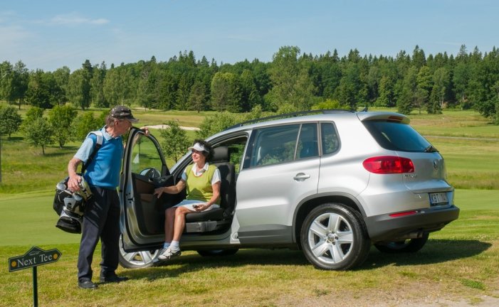donna al posto del guidatore mentre esce dalla macchina grazie alla rotazione del sedile, in un campo da golf