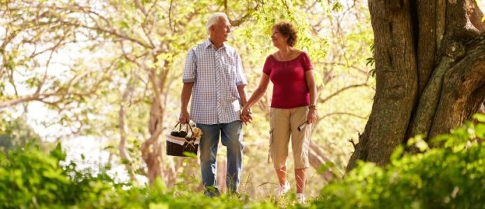 dettagli delle mani di due uomini seduti uno di fronte all'altro, uno dei quali indossa un camice, porta uno stetoscopio al collo e scrive su una cartellina