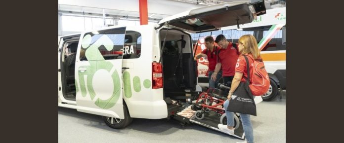 visitatori della fiera REAS provano a far salire una carrozzina su un veicolo allestito per trasporto di persone con disabilità