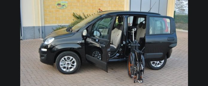 auto con un verricelloche carica all'interno la carrozzina richiusa