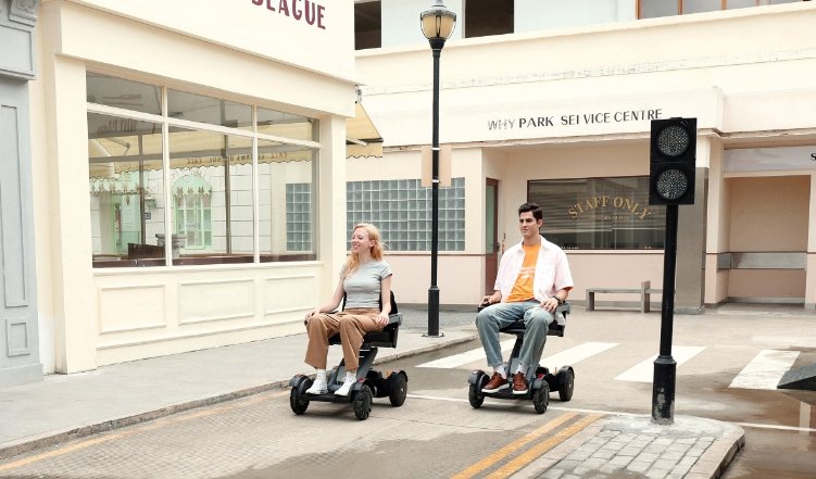 due ragazzi usano entrambi la carrozzina elettrica per passeggiare in una città
