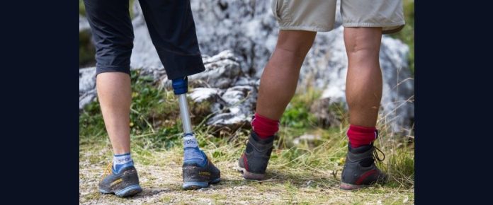 dettaglio delle gambe e scarponi indossati da due persone di spalle, delle quali una indossa una protesi