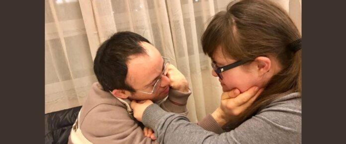 Un uomo e una donna con sindrome di Down si scambiano carezze
